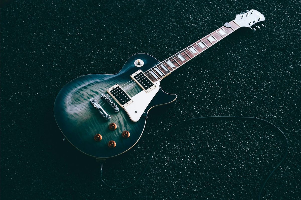 An electric guitar and its cable lying on a dark carpet