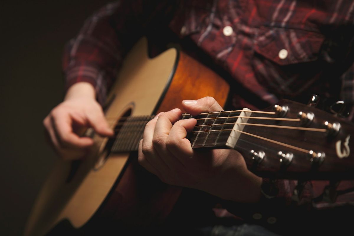 Man in a checked shirt playing an acoustic guitar