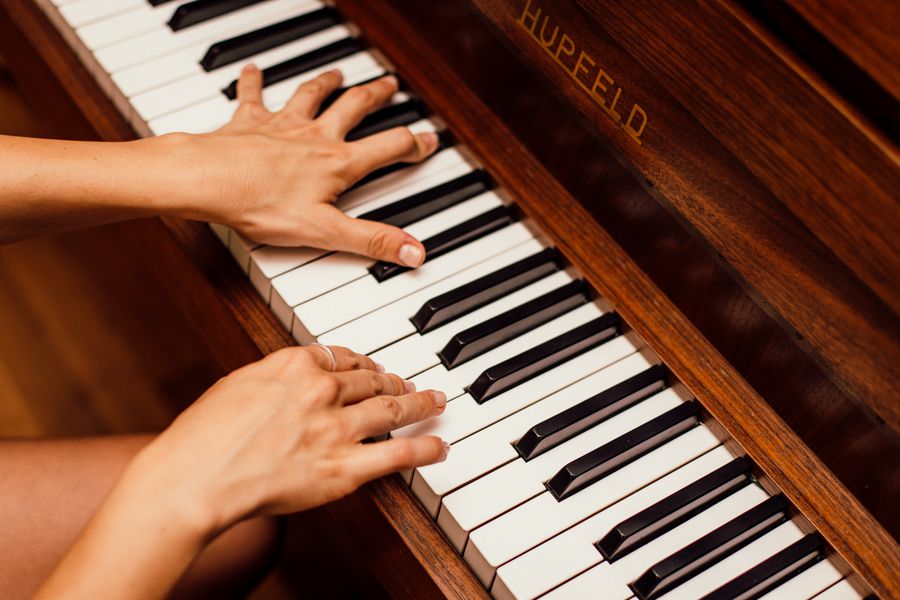 Two hands playing the keys of an upright piano