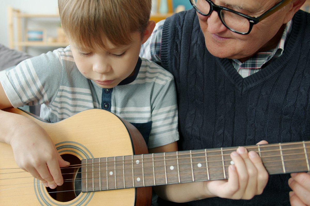 Grandfather teaching his young grandson to play an acoustic guitar
